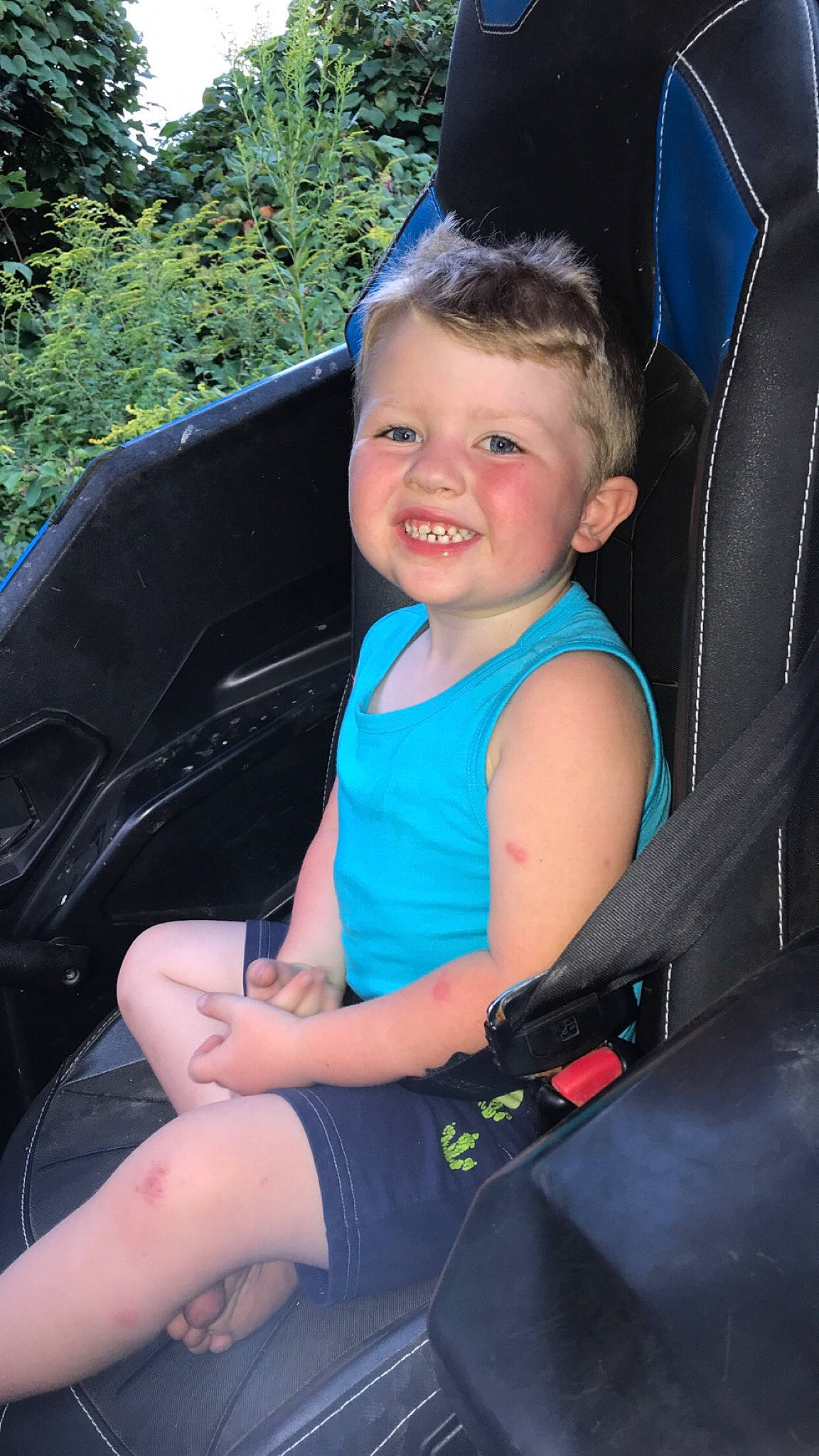 Carter is registered to the contest to win money with this photo: auto_part, car_seat, car_seat_cover, chair, electric_blue, facial_expression, fun, grass, happy, joy, lap, leisure, motor_vehicle, person, plant, recreation, sitting, smile, steering_wheel, thigh