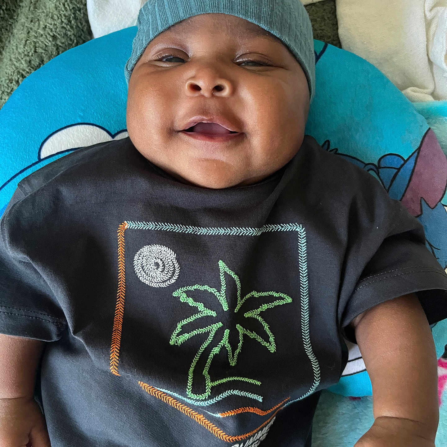 Jaking joined the competition — help win amazing prizes! baby, infant, child, portrait, face, smiling, knit_cap, black_shirt, palm_tree, clothing, cushion, blanket, indoor, closeup, sitting, lying_down, hands, arms, happy, photography