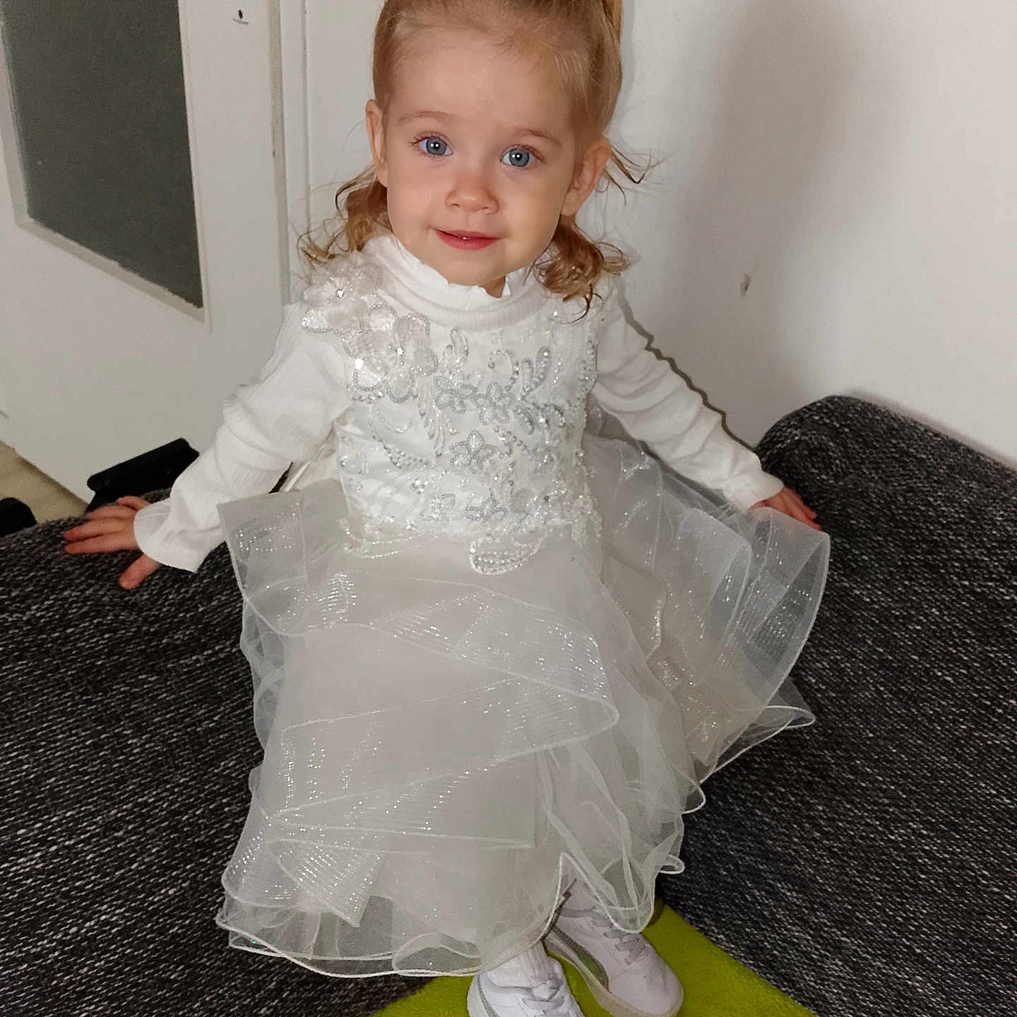 Mylanna participe au concours pour gagner de l'argent avec cette photo : blue_eyes, carpet, child, couch, curly_hair, cute, face, fashion, floor, girl, indoors, pony_tail, portrait, sitting, smile, sneakers, toddler, white_dress, white_wall, young