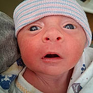 Carson is registered to the contest to win money with this photo: newborn, baby, infant, hat, close_up, face, eyes, mouth, blanket, striped_hat, person, skin, expression, cute, child, young, indoors, portrait, headwear, clothing