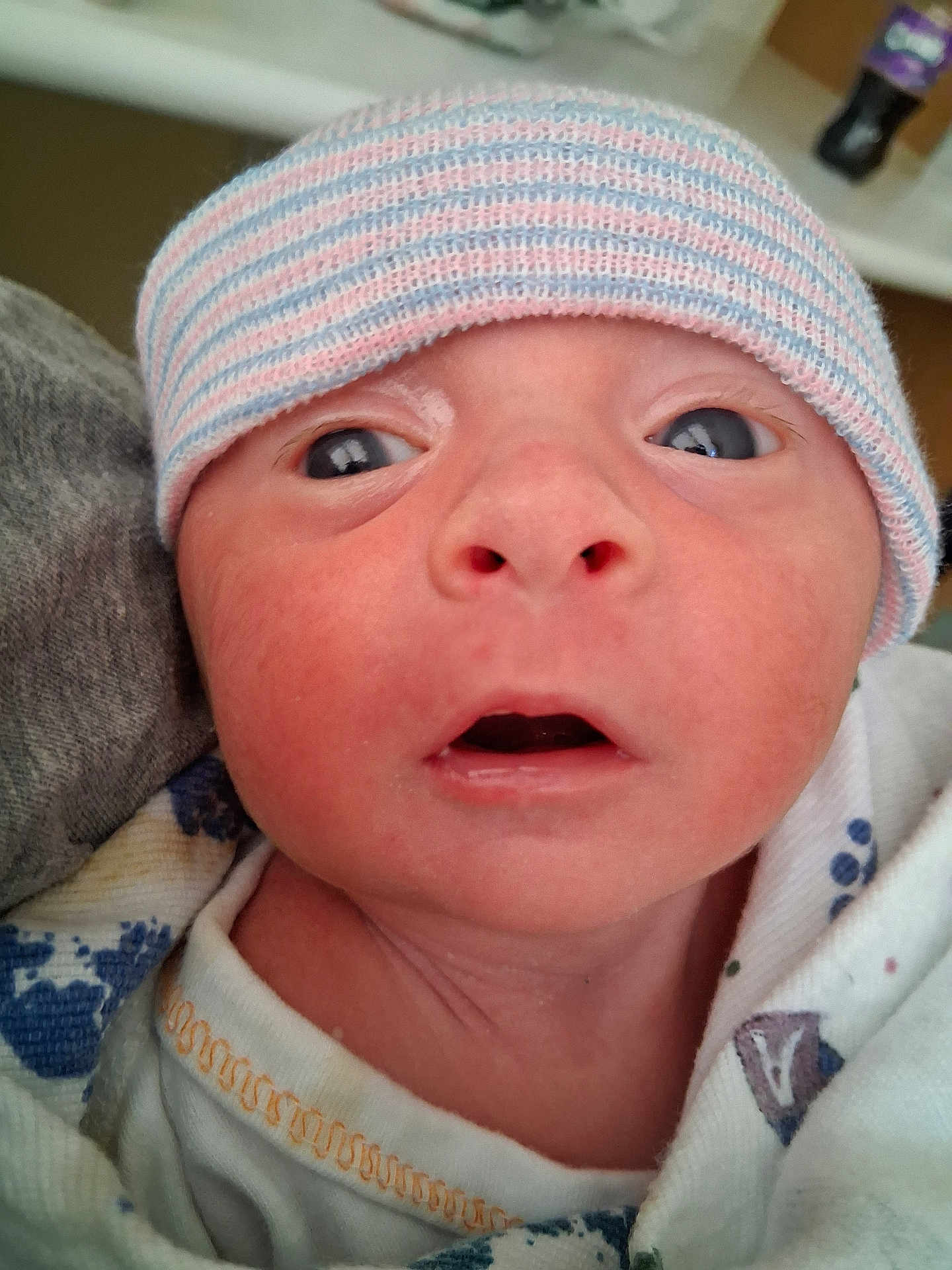 Carson is registered to the contest to win money with this photo: newborn, baby, infant, hat, close_up, face, eyes, mouth, blanket, striped_hat, person, skin, expression, cute, child, young, indoors, portrait, headwear, clothing