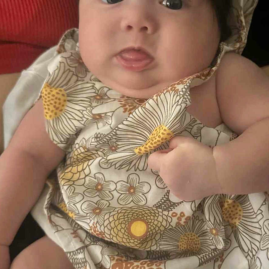 Dainary joined the competition — help win amazing prizes! arm, baby, child, curious, cute, expression, face, floral_dress, flower_headband, hand, head, indoors, infant, legs, person, portrait, sitting, skin, soft_lighting, wide_eyes