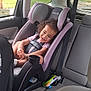 child, toddler, car_seat, smiling, curly_hair, car_interior, toy, seat_belt, window, vehicle, happy, safety, pink, gray, clothing, young_child, curtain, daylight, suburban, portrait