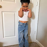 Makiah is registered to the contest to win money with this photo: blue_jeans, carpet, casual_clothing, child, curly_hair, cute, door, fashion, gray_shoes, happy, indoor, person, playful, pose, room, smile, standing, wall, white_top, young