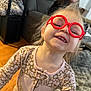 Peyton joined the competition — help win amazing prizes! child, toddler, glasses, red_glasses, smile, happy, indoor, living_room, carpet, woman, adult, furniture, couch, wood_floor, person, playful, face, hair, clothing, portrait