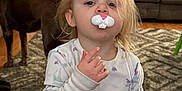 Peyton joined the competition — help win amazing prizes! toddler, child, indoor, pajamas, unicorn_pattern, pacifier, bunny_shape, dog, brown_dog, carpet, couch, window_blinds, toy_basket, living_room, person, curly_hair, floor, wood_floor, furniture, cute