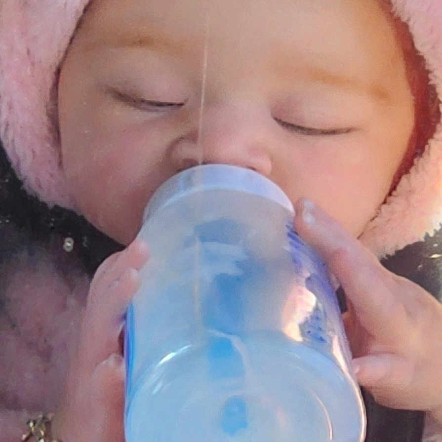 Daisy Mae joined the competition — help win amazing prizes! baby, infant, sleeping, bottle, feeding, pink_hood, fluffy, close_up, portrait, face, hands, cozy, blanket, indoor, sitting, resting, child, soft_lighting, vertical_photo, adorable