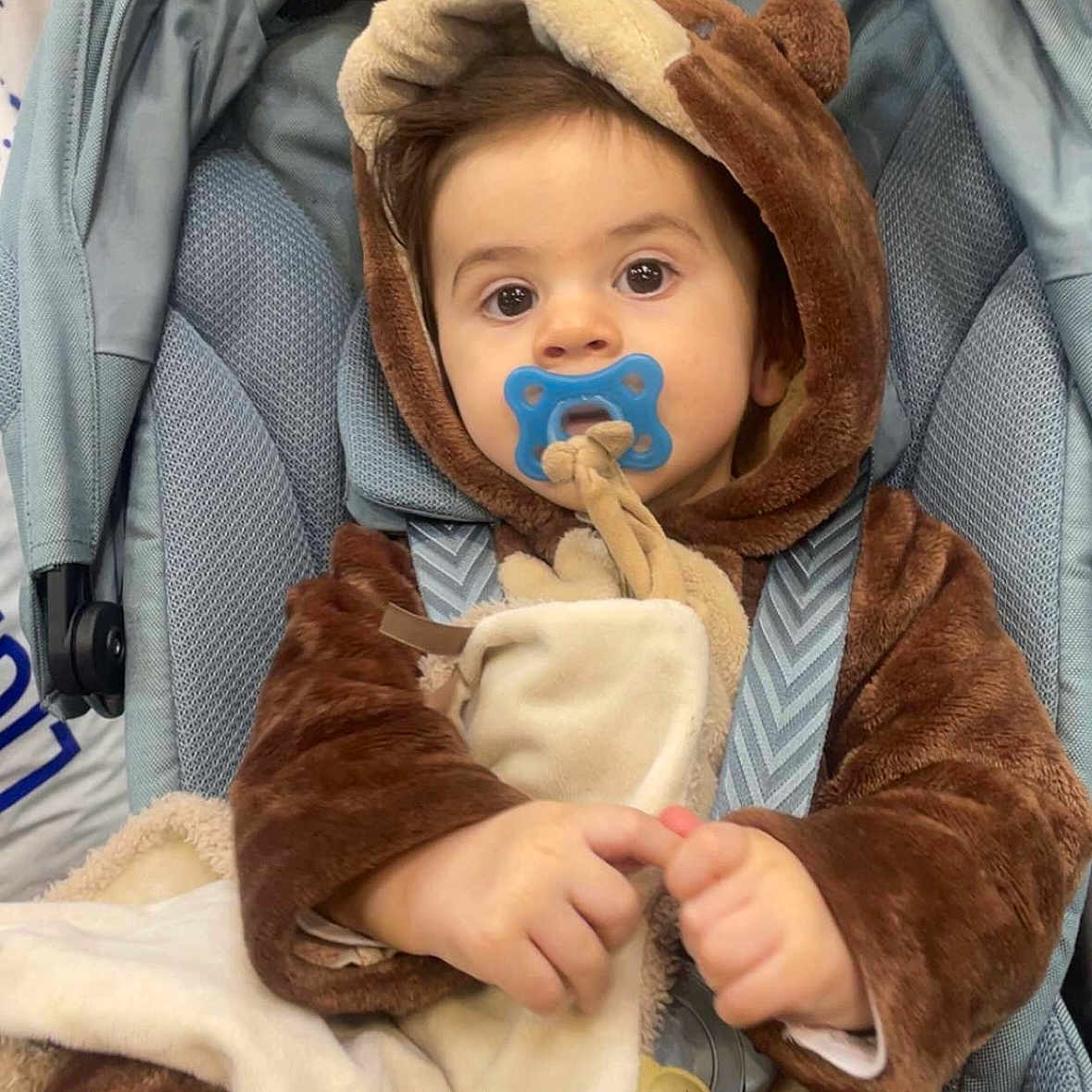 Eden participe au concours pour gagner de l'argent avec cette photo : baby, bear_costume, blanket, blue_pacifier, brown_clothing, car_seat, child, cute, face, fuzzy_clothing, hands, hooded_outfit, indoor, infant, looking_at_camera, pacifier, portrait, seatbelt, soft_toy, young_child