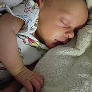 Leland Matthew is registered to the contest to win money with this photo: baby, newborn, infant, sleeping, blanket, hand, onesie, soft_texture, closeup, peaceful, cozy, portrait, skin, bed, bedding, nap, tiny_hand, face, fabric, cartoon_print