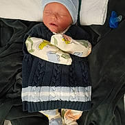 Leland Matthew is registered to the contest to win money with this photo: baby, newborn, infant, sleeping, hat, mittens, blanket, pacifier, knitted_sweater, patterned_footies, pillow, bed, cozy, portrait, closed_eyes, cute, nursery, soft_textile, freshborn, resting
