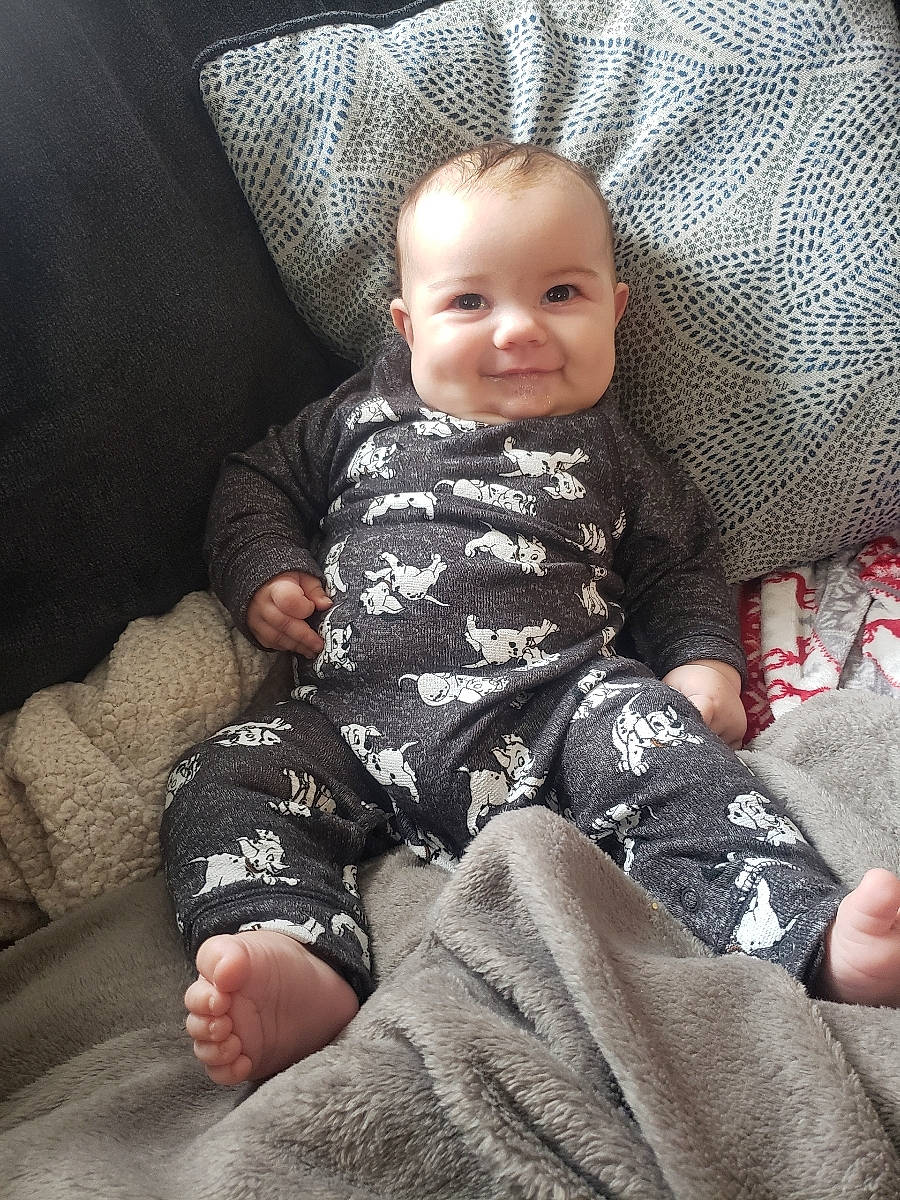 Koen is registered to the contest to win money with this photo: baby, baby_toddler_clothing, cheek, child, clothing, comfort, cool, eye, facial_expression, head, human_leg, joy, knee, lap, pattern, person, sitting, skin, sleeve, smile