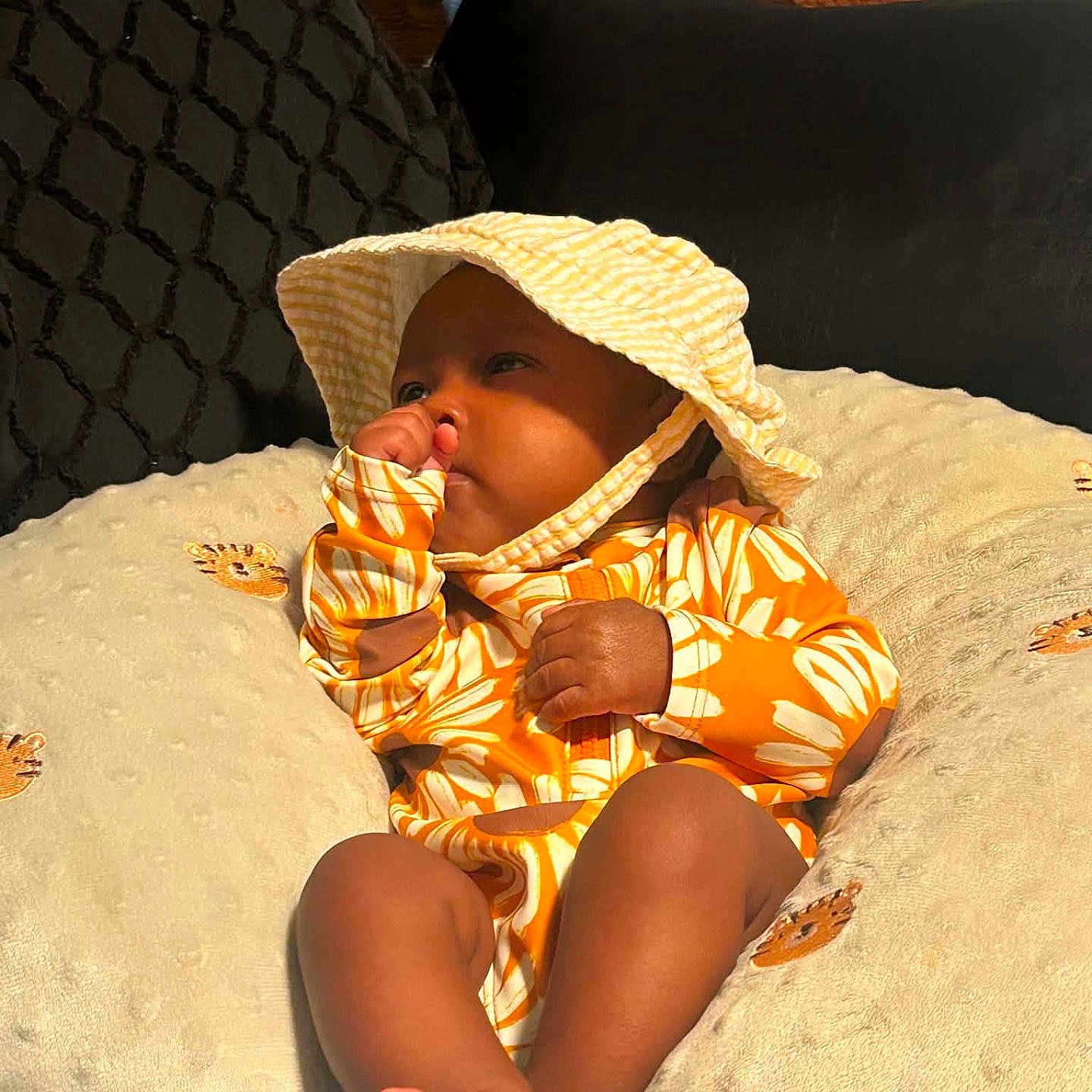 Arya is registered to the contest to win money with this photo: baby, infant, child, hat, yellow, floral_outfit, pillow, thumb_sucking, cute, indoors, soft_texture, relaxed, portrait, foot, cozy, sleepy, comfort, toddler, closeup, person