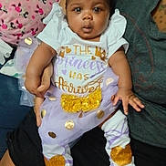 Promise is registered to the contest to win money with this photo: baby, child, tutu, headband, bow, gold, white_clothing, purple, sitting, person, cute, infant, legs, hands, face, eyes, adult_hand, fabric, pattern, indoor