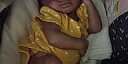 Promise is registered to the contest to win money with this photo: baby, sleeping, infant, yellow_outfit, blanket, pink_booties, cozy, dark_background, soft_texture, peaceful, child, newborn, resting, cute, indoor, portrait, clothing, person, infantwear, toddler