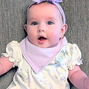 Sarah-Kate joined the competition — help win amazing prizes! baby, infant, headband, flower, purple, bib, clothing, floral, couch, texture, expression, surprised, face, child, person, sitting, indoors, cute, young, portrait