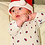 baby, infant, santa_hat, onesie, red, white, blue, sailboat_pattern, cute, holiday, christmas, soft, pillow, lying_down, chubby_hands, face, eyes, indoor, portrait, child