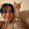 woman, tattoos, kitten, cat, pet, smiling, shoulder, neck, orange_cat, indoor, couch, leather, casual, tank_top, portrait, cute, animal, feline, young, happy