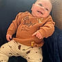 acorn_pattern, baby, blue_chair, child, clothing, cozy, cute, happy, illustration, indoor, infant, patterned_pants, plush, pointing, portrait, smiling, soft_light, sweatshirt, text, toddler