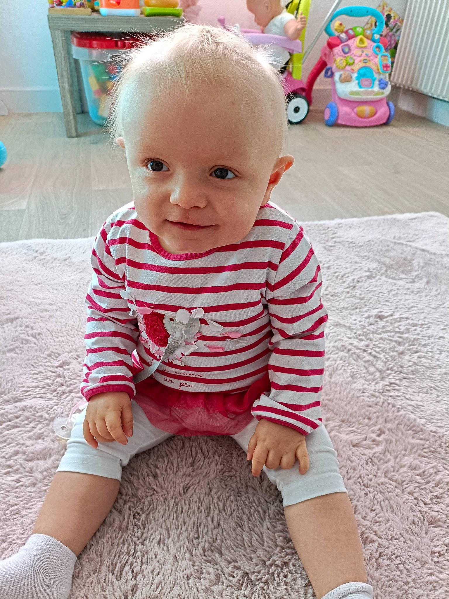 Louna participe au concours pour gagner de l'argent avec cette photo : baby, baby_toddler_clothing, cheek, child, floor, flooring, happy, human_leg, joint, knee, pattern, person, play, product, sitting, skin, sleeve, smile, t_shirt, thigh