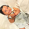 baby, infant, child, smiling, happy, portrait, close_up, lying_down, blanket, white_blanket, pajamas, striped_clothing, bracelet, dark_hair, brown_eyes, indoor, cozy, soft_lighting, baby_portrait, adorable