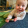 baby, child, toy, carpet, indoor, blue_eyes, clothing, hand, face, smiling, floor, furniture, playroom, person, crawling, infant, home, cute, curious, light