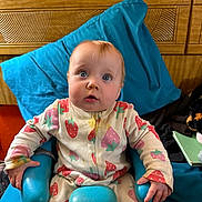 Valkyrie joined the competition — help win amazing prizes! baby, child, infant, onesie, strawberry_pattern, blue_chair, wooden_headboard, orange_wall, curious_expression, indoor, seated, pajamas, cute, person, young_child, furniture, portrait, face, hand, soft_lighting