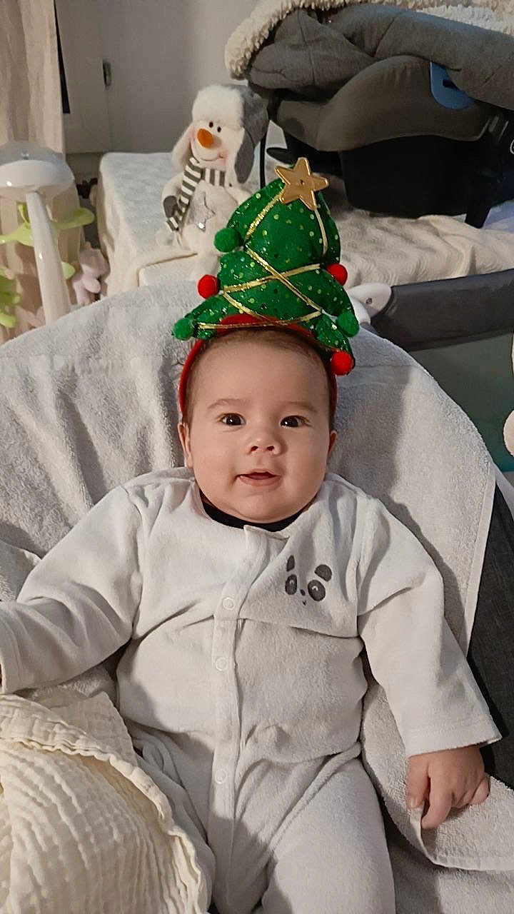 Jalil a rejoint le concours — aidez-le/la à gagner de superbes lots ! baby, child, christmas_tree_headband, festive, holiday, onesie, panda_design, plush_toy, snowman, soft_blanket, smiling, indoors, cute, headwear, happy, seated, infant, cozy, decor, celebration