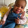 baby, child, denim_overalls, pink_shirt, bow, smile, thumbs_up, unicorn_cushion, colorful, cute, happy, indoors, portrait, sitting, face, human, infant, clothing, playful, headwear