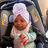 baby, infant, car_seat, headwrap, flower, smile, happy, child, clothing, bib, toy, pacifier, seatbelt, indoors, cute, hand, portrait, person, baby_girl, cozy