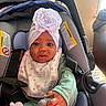 baby, car_seat, headwrap, flower, bib, clothing, hand, infant, indoors, seatbelt, pacifier, pink, purple, green, cute, child, person, portrait, toddler, soft_lighting