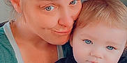 Kodi is registered to the contest to win money with this photo: woman, baby, child, holding, blanket, blue_eyes, close_up, portrait, indoor, casual_clothing, smile, face, hair_bun, skin, hand, love, family, tenderness, affection, candid