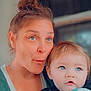Kodi is registered to the contest to win money with this photo: woman, baby, child, portrait, face, blue_eyes, blanket, holding, expression, indoor, casual_clothing, hair_bun, curly_hair, close_up, skin, person, family, mother_and_child, cute, soft_light