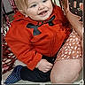 toddler, child, red_hoodie, smile, happy, indoor, person, legs, arm, floor, phone_screen, photo_editing, crop_tool, filter_icon, blue_eyes, blonde_hair, striped_socks, patterned_skirt, close_up, casual_clothing