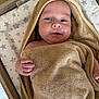baby, towel, hood, infant, face, skin, hand, blanket, bed, changing_pad, star_pattern, wood, furniture, cute, child, young, wrapped, portrait, indoors, smiling
