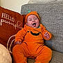 baby, child, couch, cozy, cute, fabric, happy, headwear, home, indoor, laughing, orange, person, pillow, plush, portrait, pumpkin_costume, seated, smiling, soft_lighting