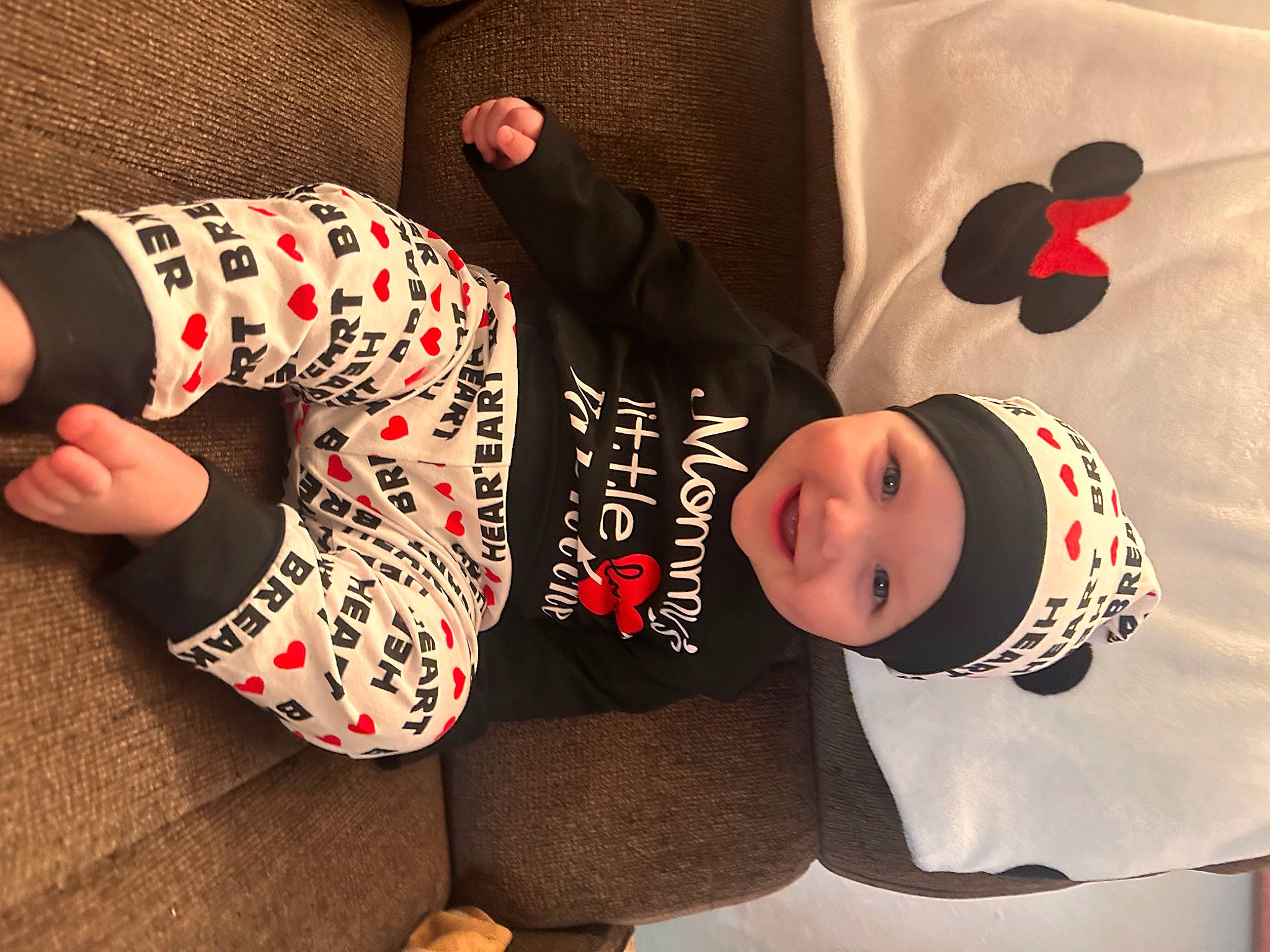 Jackson is registered to the contest to win money with this photo: arm, baby_toddler_clothing, carmine, child, comfort, elbow, facial_expression, flooring, foot, headwear, human_body, human_leg, joy, knee, pattern, person, sleeve, sportswear, t_shirt, thigh