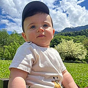 Karl participe au concours pour gagner de l'argent avec cette photo : baby, child, cap, tshirt, giraffe_print, outdoor, nature, grass, mountain, sky, clouds, sunny, greenery, portrait, cute, sitting, daylight, person, face, young