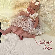 Lakelynn joined the competition — help win amazing prizes! baby, infant, dress, headband, bow, lace, quilt, blanket, embroidered_text, pink, white, cute, smiling, portrait, child, sitting, indoors, fabric, soft, cozy