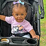 toddler, child, stroller, smile, bow, hair, clothing, shirt, minnie_mouse, baby, outdoor, seatbelt, foot, hand, person, cute, happy, portrait, playful, grass