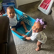 Seven is registered to the contest to win money with this photo: barefoot, bow, carpet, child, clothing, curious, door, furniture, happy, home, indoor, laundry_basket, person, plastic_bag, playful, shorts, smile, toddler, toy, white_shirt