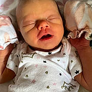 Sophia is registered to the contest to win money with this photo: newborn, baby, sleeping, infant, clothing, white_outfit, stars_pattern, crown_pattern, blanket, soft_texture, peaceful, closeup, face, hands, cute, resting, indoors, portrait, sleep, child