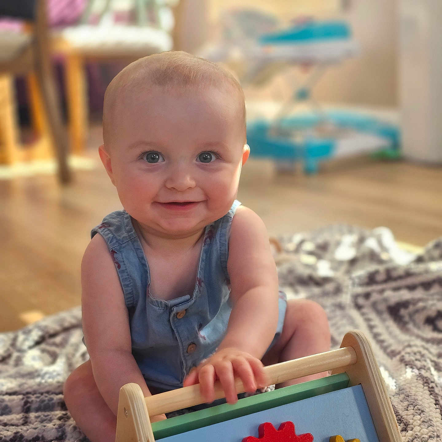 Hogan joined the competition — help win amazing prizes! baby, child, smiling, toy, wooden_toy, colorful, indoor, blanket, floor, sitting, cute, happy, face, person, home, bright, daylight, infant, clothing, play