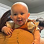 baby, child, person, smiling, tongue_out, blue_eyes, indoor, kitchen, adult, holding, clothing, beige, orange, hair, cabinet, facial_expression, cute, happy, portrait, family