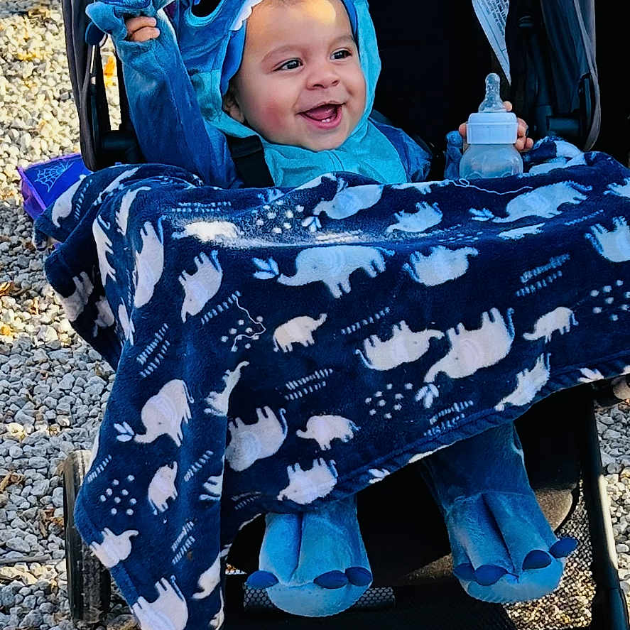 Terrance is registered to the contest to win money with this photo: alloywheel, baby, bonnet, car, carwheel, clothing, face, happy, hat, head, hood, machine, person, photography, portrait, smile, spoke, stroller, tire, transportation