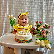 Isabella is registered to the contest to win money with this photo: baby, birthday_cake, celebration, child, decor, flowers, food, happy, headband, high_chair, indoor, number_candle, person, portrait, roses, smiling, table, tulips, white_tights, yellow_clothing