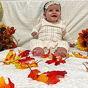 Isabella is registered to the contest to win money with this photo: baby, child, smiling, knitwear, headband, autumn, fall_leaves, flowers, pumpkin, decorations, indoors, white_blanket, cute, celebration, portrait, sitting, happy, seasonal, festive, colorful
