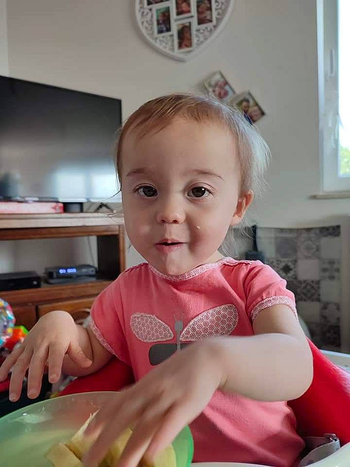 émilia participe au concours pour gagner de l'argent avec cette photo : baby, baby_toddler_clothing, chair, child, comfort_food, cooking, fun, happy, home_appliance, kitchen, kitchen_appliance, person, picture_frame, room, sitting, t_shirt, table, tableware, thumb, toddler