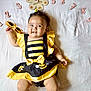 Anaya is registered to the contest to win money with this photo: baby, infant, smile, yellow, black, dress, sunglasses, flower, numbers, white_background, milestone, cute, child, lying_down, happy, headband, shoes, month_marker, person, portrait