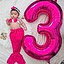 Anaya is registered to the contest to win money with this photo: baby, infant, mermaid_costume, pink, balloon, number_3, seashells, white_background, headband, crochet, cute, lying_down, celebration, soft_texture, decor, child, portrait, holiday, festive, playful