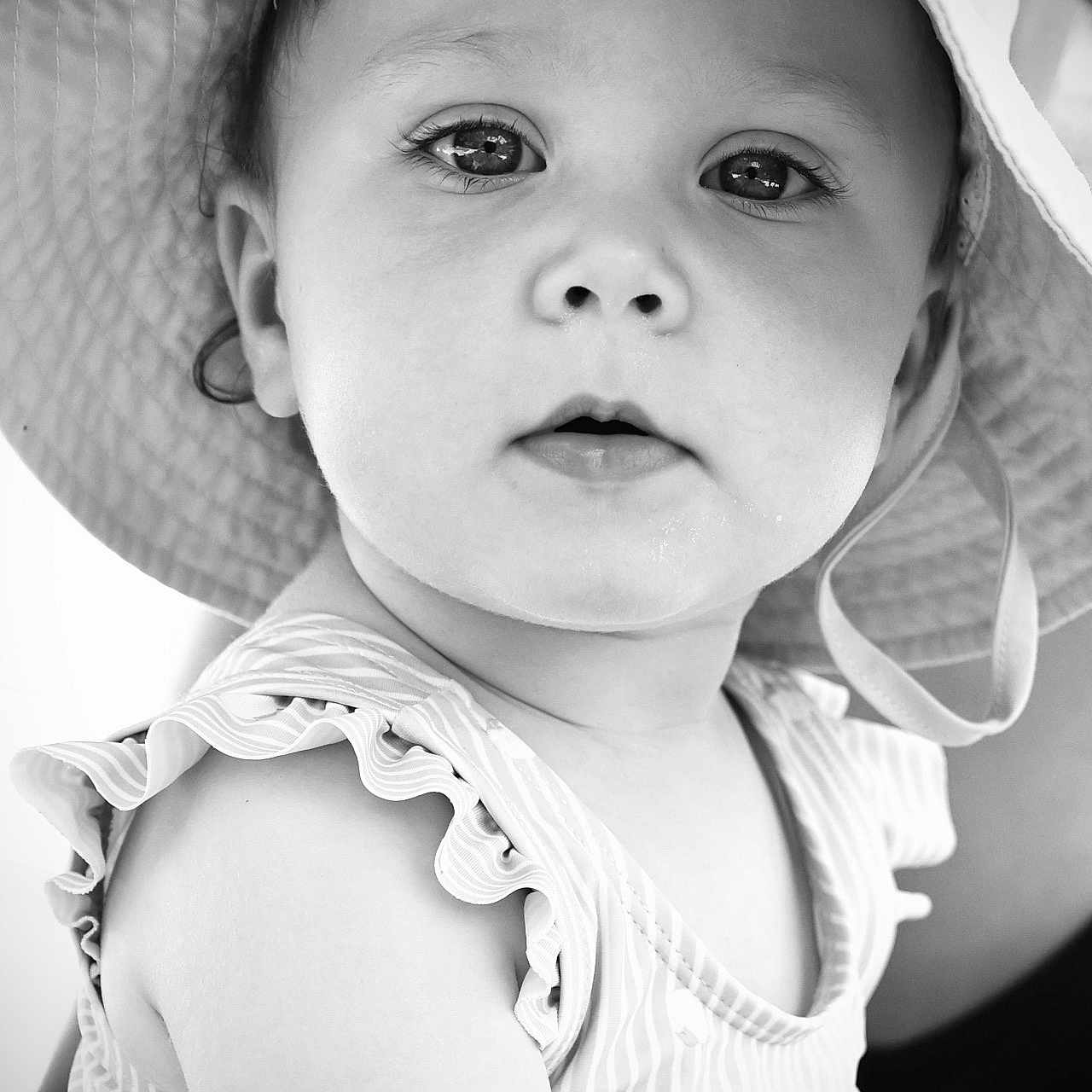 Mia a rejoint le concours — aidez-le/la à gagner de superbes lots ! baby, black_and_white, child, closeup, clothing, curious, cute, expression, eyes, face, hat, headwear, outdoor, person, portrait, skin, sleeveless, striped, summer, toddler